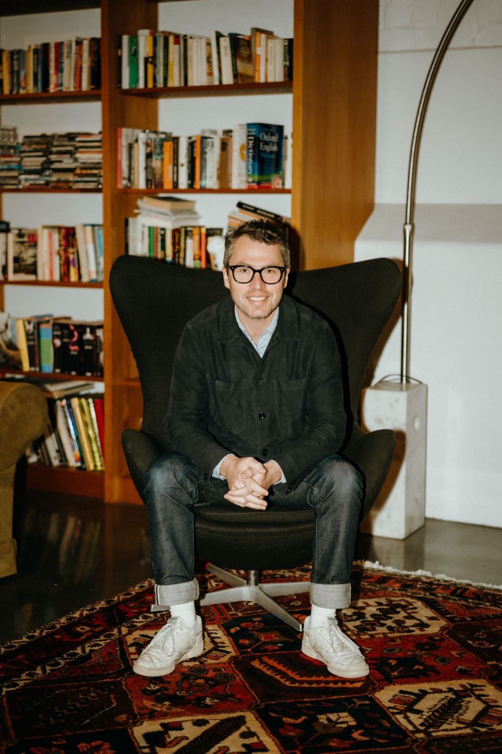 Barney Chunn, CEO and co-founder of Drumbeat, sitting in an egg chair in front of a bookshelf