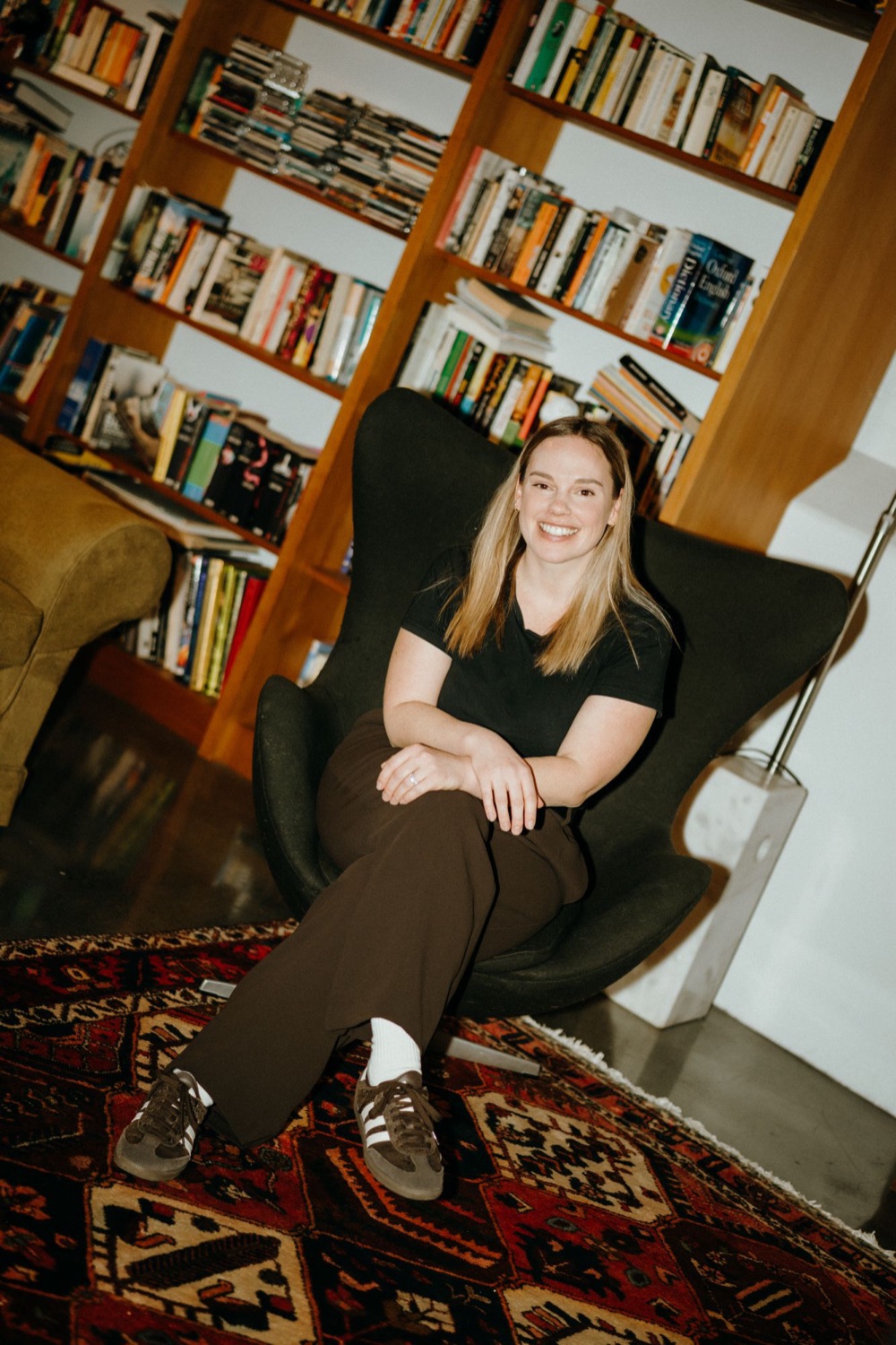 Jessie Gilchrist, Comms Lead at Drumbeat, sitting in an egg chair in front of a bookshelf